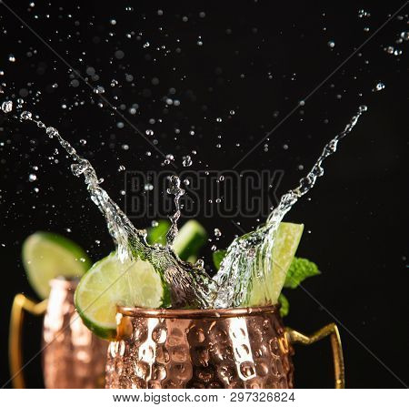 Famous splashing Moscow mule alcoholic cocktail in copper mugs, freeze motion effect.