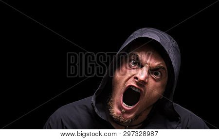 Angry Scarry Shouting Man In A Hood On A Black Background.