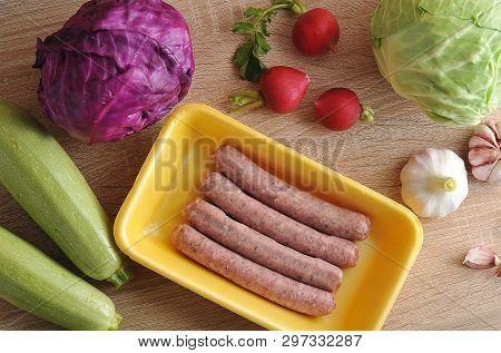 Raw Meat Sausages Kupaty And Vegetables - Cabbage, Zucchini, Radish And Garlic On Wooden Background 