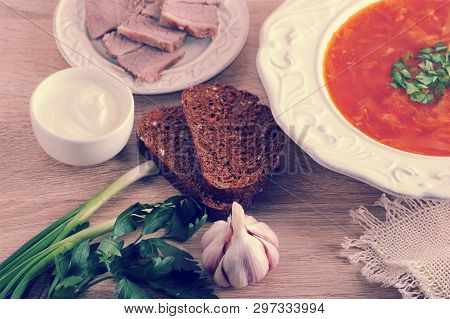 Soup In A Bowl With Dill, Sour Cream, Beef And Black Bread On Wooden Background - Top View - Borsh -