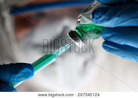 Pharmacist Syringe Dosing Green Liquid Vaccine. Scientist Holding Injection Needle In Hands In Blue 