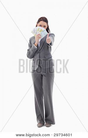 Businesswoman approving and hiding with bank notes in her hand against white background
