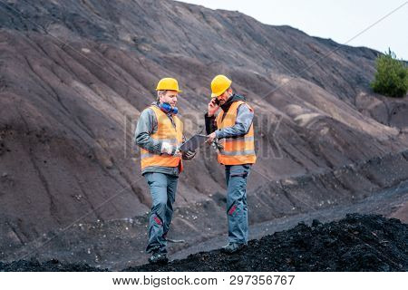 Workers standing in open-cast mining operation pit