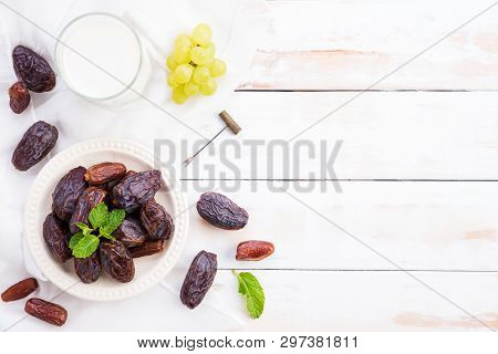 Ramadan Food And Drinks Concept. Milk With Dates Fruit, Grape And Mint Leaves On A White Wooden Tabl