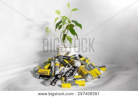 Moscow, Russia - April 20, 2019: A Live Flower In A Pot Grows From A Pile Of Batteries. Problems Of 