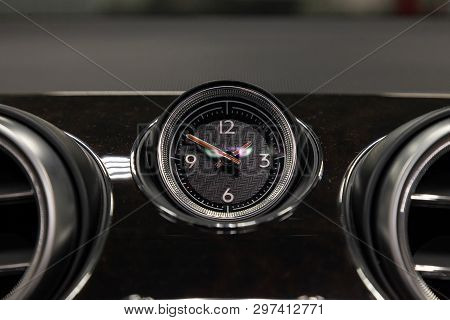 The Watch On The Dashboard Of An Expensive Car Is Close-up, Covered With Natural Black Leather And B