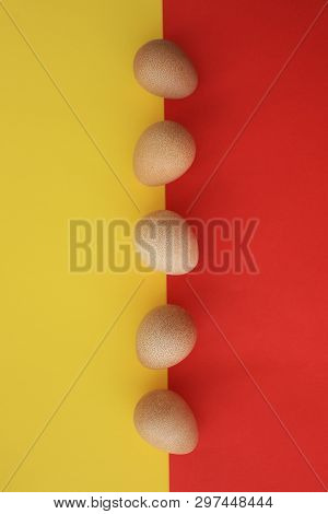 Five Eggs Of Guinea Fow Positioned In The Middle Of The Picture On Yellow And Red Background.
