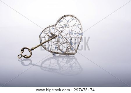 Key And A Heart Shaped Metal Cage On White