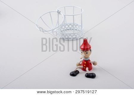 Metal Cage And Little Puppet Pinocchio Made Of Wood