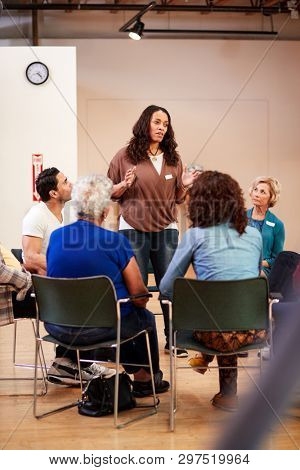 Woman Standing To Address Self Help Therapy Group Meeting In Community Center