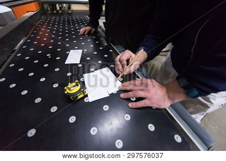 two young carpenters calculating and programming a cnc wood working machine in workshop. wood workers preparing a computer program for CNC machine at big modern carpentry