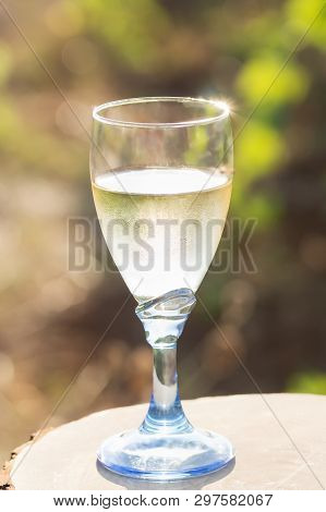 One Glass Of Fresh White Wine On A Wooden Board On A Bright Sunny Day In A Vineyard In Salento, Apul
