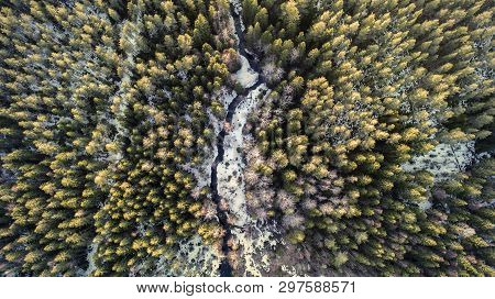 Aerial View Of A River In The Forest With Snow Along The Banks.