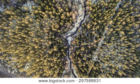 Aerial View Of A River In The Forest With Snow Along The Banks.