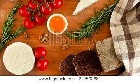 Rye Bread With Brie And Camembert Cheeses, Nuts, Honey, Cherry Tomatoes And Rosemary On A Wooden Boa