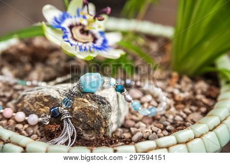 Jewelery Made Of Natural Stones Against The Backdrop Of Blossoming Pasiflora. Bracelets, Rings, Neck