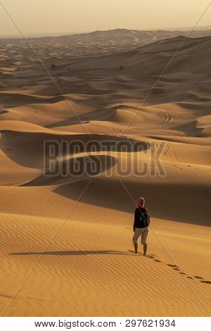 A Woman Enjoying The Stunning Views Of The Arabian Desert During Sunset.