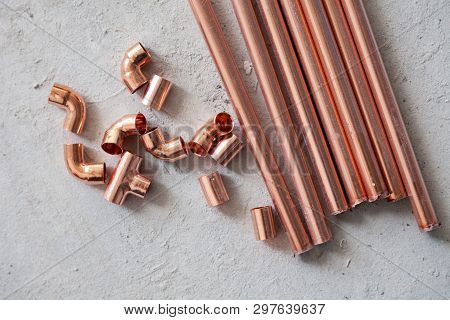 Closeup Many New Copper Dyne Pipesб Fittings On The Concrete Floor. Concept Installation, Replacemen