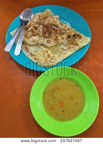 Top view of flatbread Roti canai, also known as Roti cane, Roti parotta served with dal on wooden table