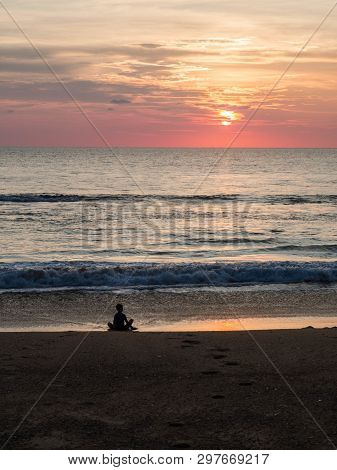 Silhouette Of An Indefinite Person In Lotus Position On A Sea Sandy Beach During A Beautiful Sunset.