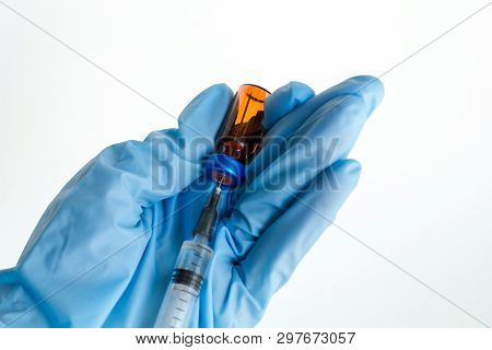 Hand In Medical Glove Picking Medication Into The Syringe From Red Ampoule On A White Background