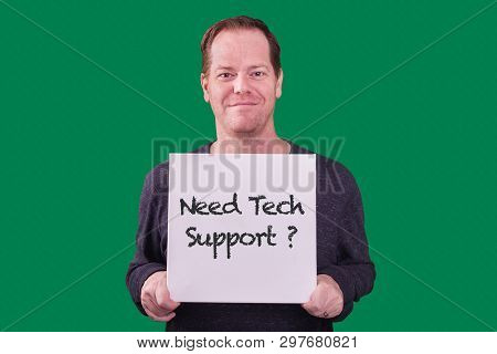 Red Headed Adult Man Holding A Need Tech Support? Sign Smiling Photographed On Green Screen Backgrou