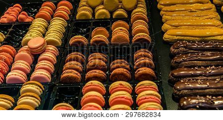 Many Colorful Makaroons And Chocolate And Caramel Eclair With Nuts And Cream On Display