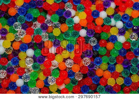 Tiny jelly-like beads with bumpy textured surfaces in many colors creating a multicolored background.