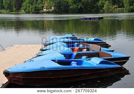 Row Of Blue Paddleboats Lying At Jetty At A Lake In Summer