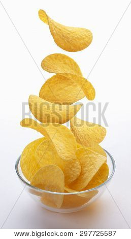 Potato Chips Falling Into Glass Bowl Isolated On White Background