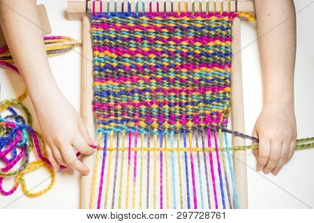 Weaving. Hands Of Little Caucasian Girl Working On Small Loom Weaving.