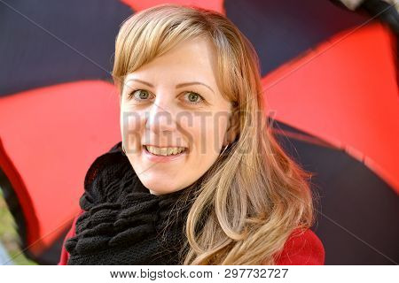 Portrait Of The Young Cheerful Woman Against A Black-red Umbrella