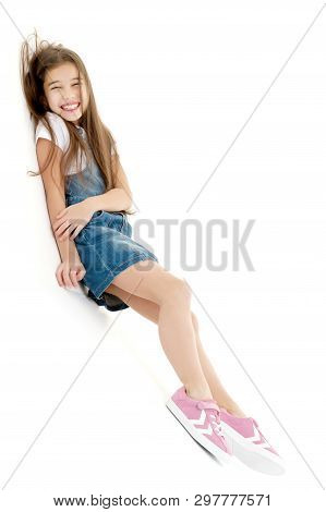 A Cute Little Girl Leaned Against A White Wall. Cyclorama In Studio. Isolated On A White Background.
