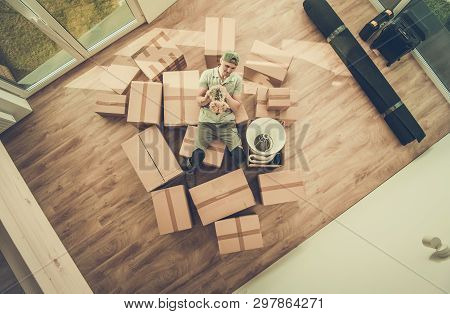 Single Men With Dog Moving In. Caucasian Men Between Moving Cardboard Boxes Filled With Personal Stu