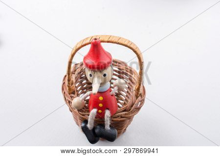 Pinochio Toy Figurine Sitting In A Straw Basket