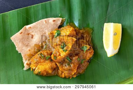 Close Up Traditional Indian Butter Chicken Curry And Lemon Served With Chapati Bread On Banana Leaf.