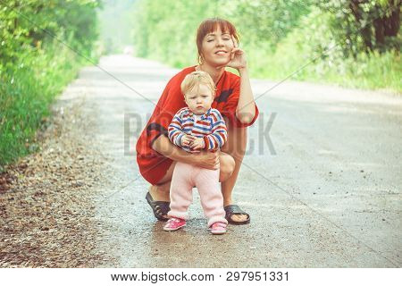 The Child Learns To Walk In The Park Barefoot On The Grass