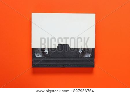 The Videotape In A Paper Case On Orange Background. Pop Culture Attributes, Minimalism. Top View