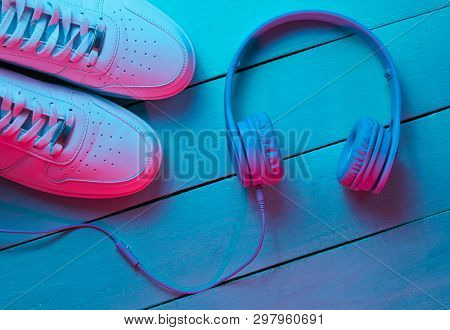 Lifestyle Concept. Sneakers And Headphones On Wooden Background. Retro Wave, Blue Red Neon Light, Ul