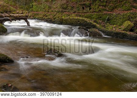 Long Exposure Of A Waterfall On The East Lyn River Flowing Through The Woods At Watersmeet In Exmoor