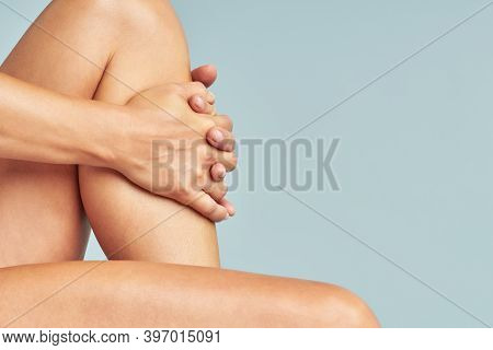 Cropped Shot Of A Woman Touching Her Soft And Silky Skin On Legs After Epilation While Sitting Over 