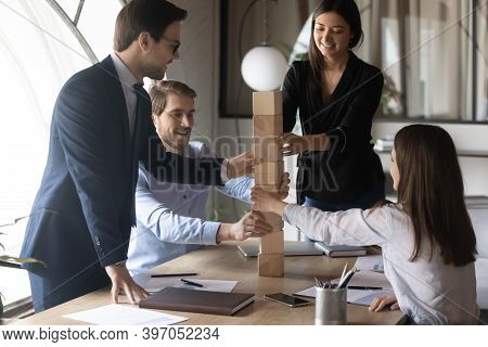 Multiethnic Coworkers Participating In Teambuilding Activity Building Column From Cubes