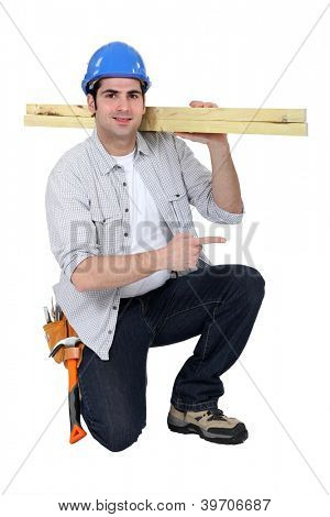 Builder transporterar trä på axel
