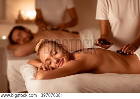 Couple Relaxing Enjoying Exotic Hot Stones Massage Lying On Beds In Luxurious Spa Center. Relaxation