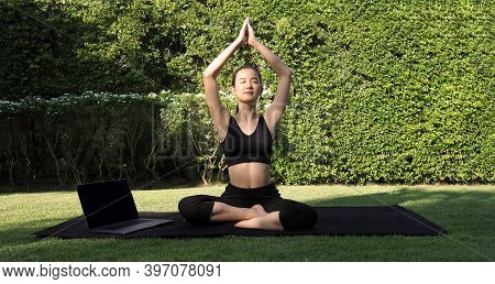 A Sporty Woman Or Online Instructor In Sportswear Is Sitting And Practicing Yoga