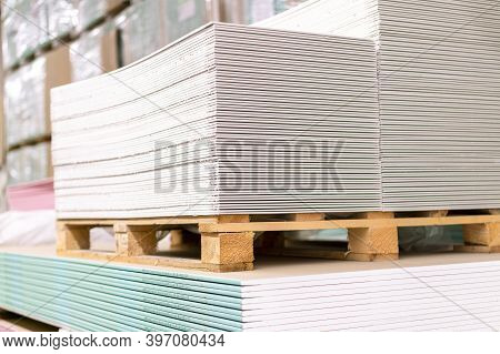 Pallet With Drywall Sheets Plasterboard In The Building Warehouse Store. Stacking Of White Gypsum Pa
