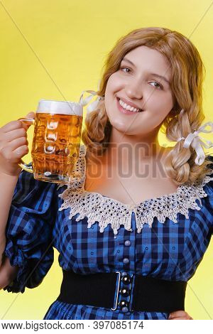 Young Woman In A Blue Dress With A Mug Of Beer On A Yellow Background