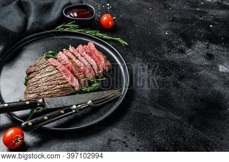 Grilled And Cut Flat Iron Steak. Marble Beef Meat. Black Background. Top View. Copy Space