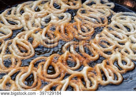 Frying Jalebi Batter In Oil. Red And Orange-colored Batter Will Be Dipped Into Sugar Syrup For A Swe