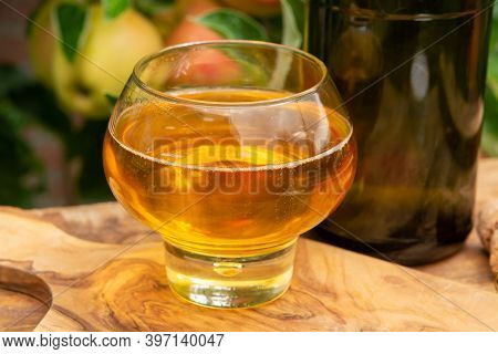 Glass Of Apple Cider From Normandy, France And Green Apple Tree With Ripe Red Fruits On Background